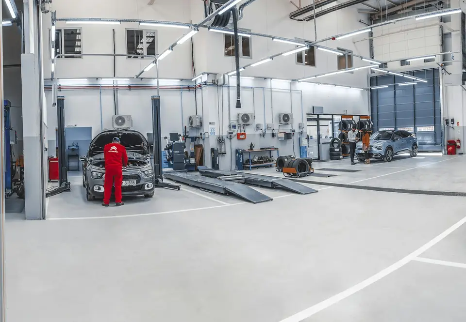 Bright auto service shop with a light-gray coated floor, white line striping and two-post lifts (stock photo)