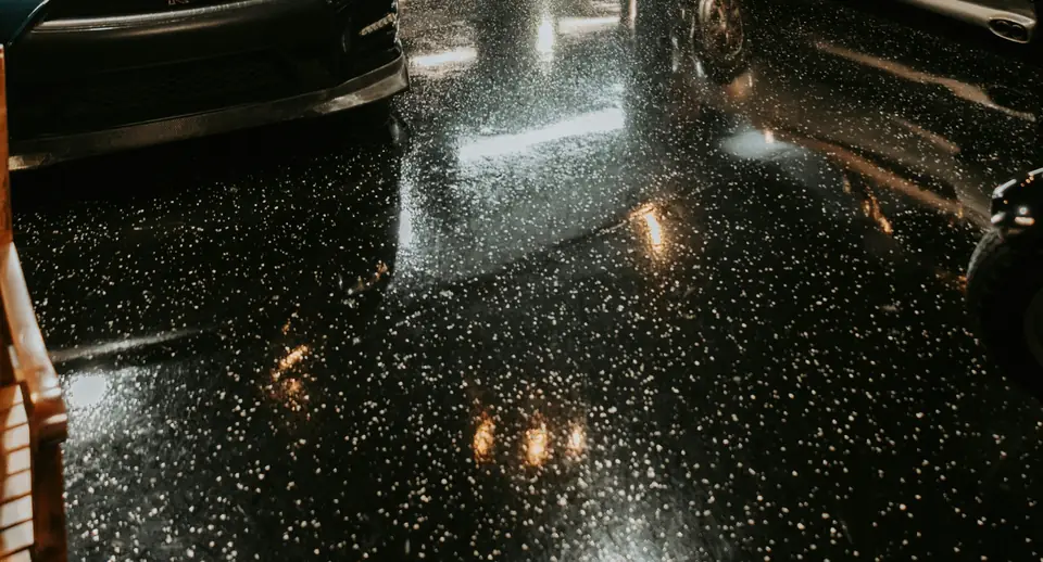 Dark, high-gloss epoxy floor with light decorative chips scattered across it in a car garage (stock photo)