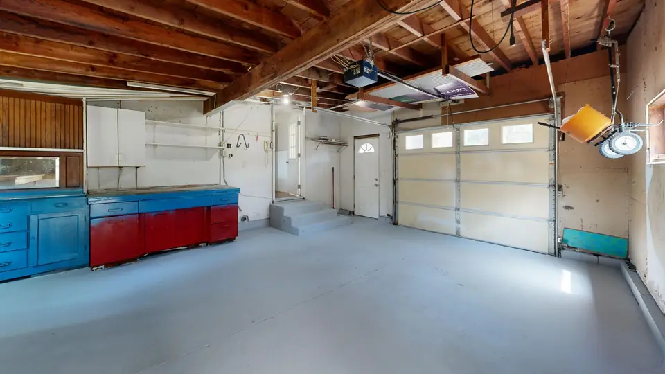 One-car garage with a painted light-gray floor, the kind of finish that has to be checked before any recoat (stock photo)