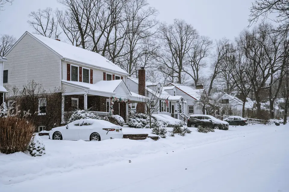 Snow-covered suburban street with attached garages and cars in the driveways (stock photo)