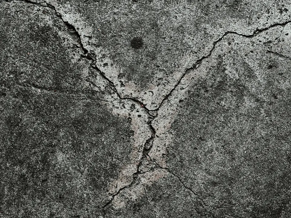 Close-up of spalled, pitted concrete with branching cracks (stock photo)