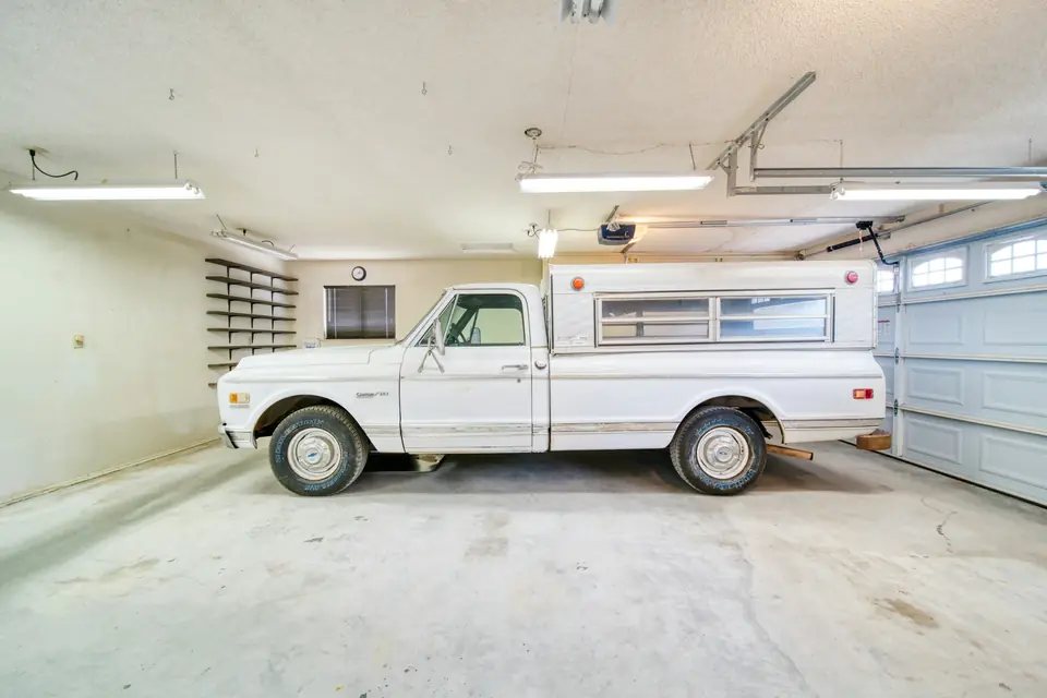 Two-car garage with blotchy, stained bare concrete and a parked pickup, the kind of slab a flake floor covers (stock photo)