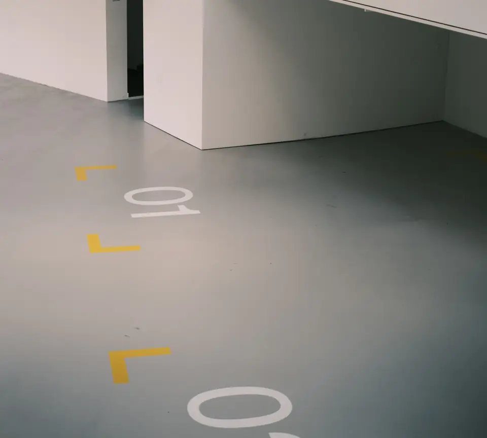 Smooth gray coated floor with yellow corner markers and painted bay numbers (stock photo)